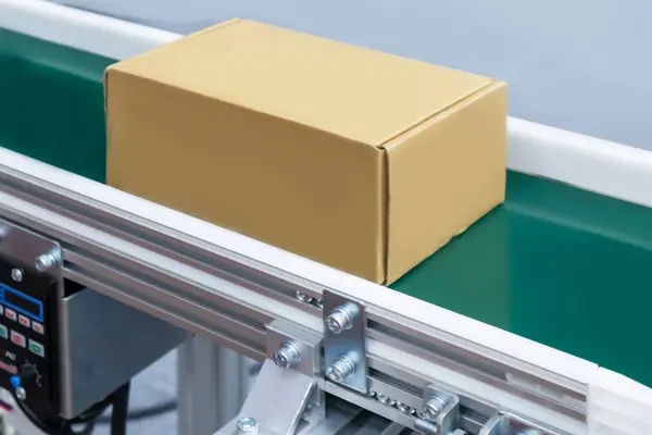 Egy automatikus szállítószalagon haladó kartondoboz, amely az ipari automatizálás példája.