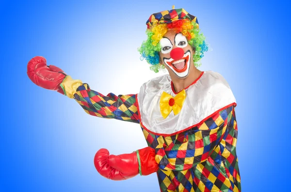Bohóc színes jelmezben és bokszkesztyűben, vidám arccal mutatkozik.