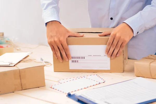 Csomagoló munka közben, doboz zárása címkével, postai környezetben.