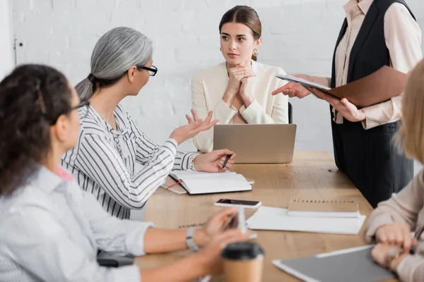 Egy csoportvezető és kollégái megbeszélés közben, a munkahelyi környezetben.