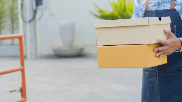 Futár két dobozt tart a kezében, kész a csomagok kiszállítására.