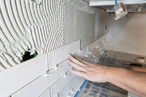 Egy hidegburkoló csempefektetést végez egy konyhában, precíz munkával.