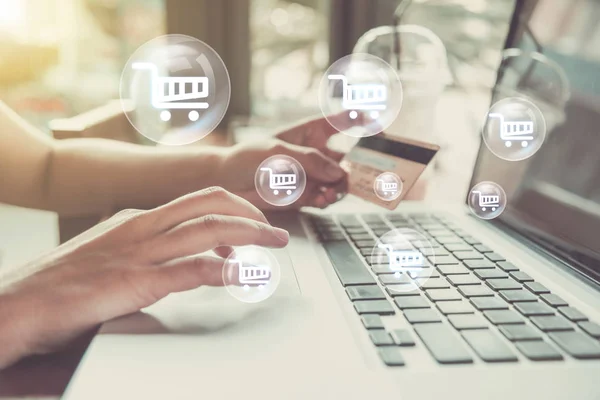 Egy kéz bankkártyát tart, miközben online vásárlást végez a számítógépen.