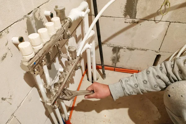 Egy csőszerelő éppen a fűtési rendszer csöveit szereli egy építkezésen.