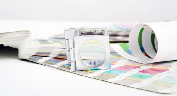 Egy színes nyomtatási mintákból álló könyv és egy lencse a nyomdaiparban.