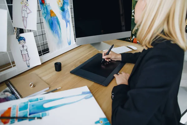 Divatszabó digitális rajzoláson dolgozik egy táblagépen.