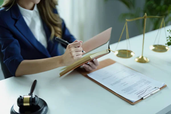 Egy fiatal ügyvéd jegyzetel egy jogi dokumentum felett, háttérben mérleg.