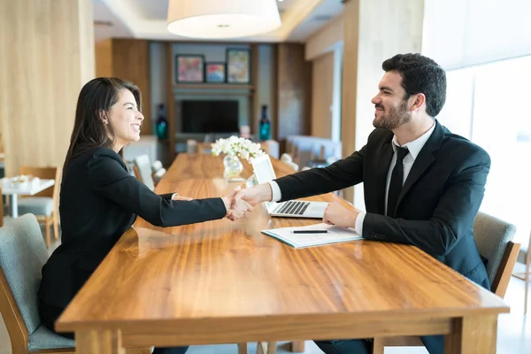Két üzletember kézfogással zárja le a megbeszélést egy modern irodában.
